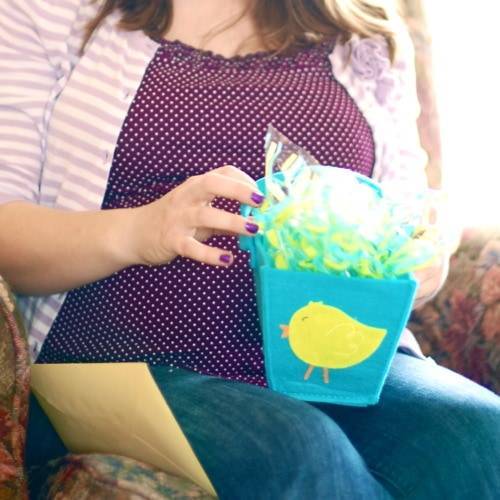 Pregnant woman opening a gift bag at a baby shower.