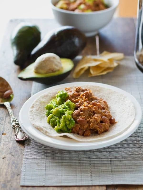Crockpot Mexican chicken and pinto beans on a tortilla.