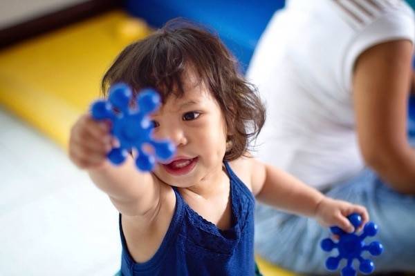 Little girl holding blue toys.