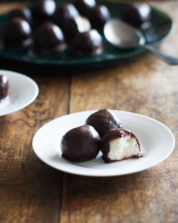 Three dark chocolate coconut bites on a white plate.