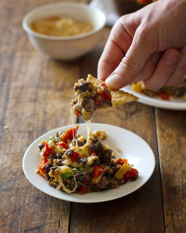 Quinoa and black bean casserole on a white plate and on a tortilla chip.