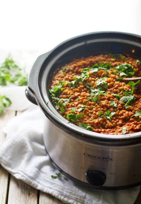 Red lentil curry in a crockpot with herbs.