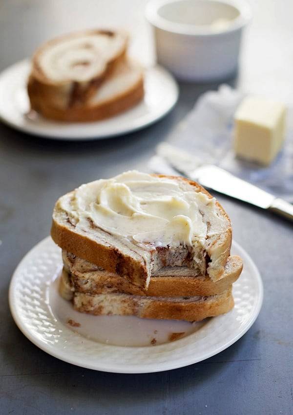 Cinnamon swirl bread with butter stacked on a plate.