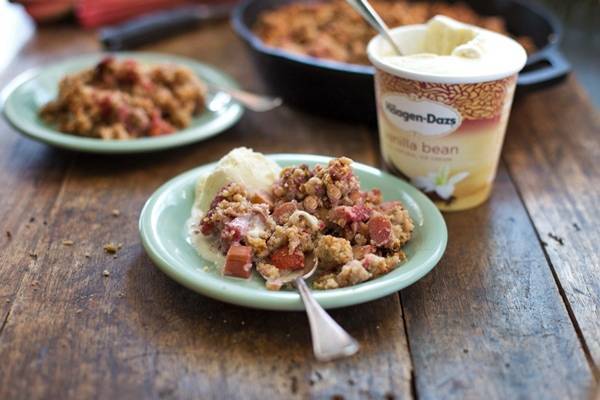 Paleo strawberry rhubarb crisp on teal plates with vanilla ice cream.