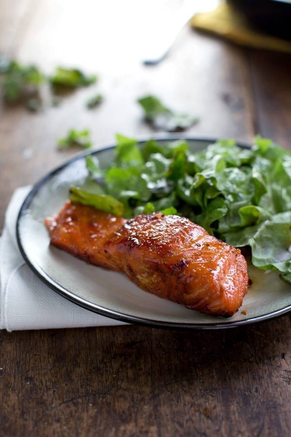 Caramelized salmon on a white plate with greens.