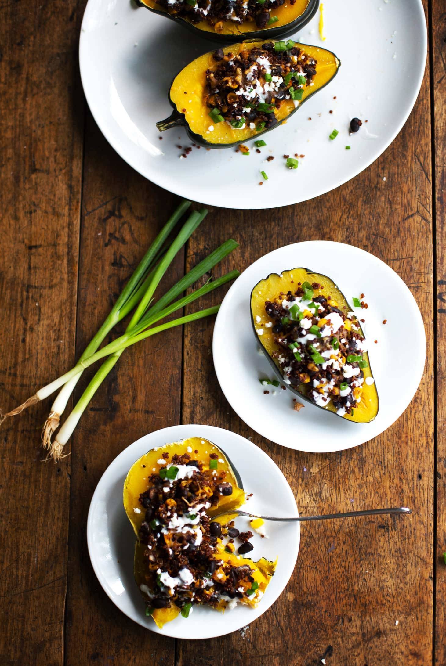 Mexican Roasted Corn and Quinoa Stuffed Squash on three white plates with green onions.