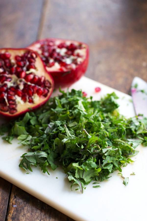 Kale and pomegranates on a cutting board.