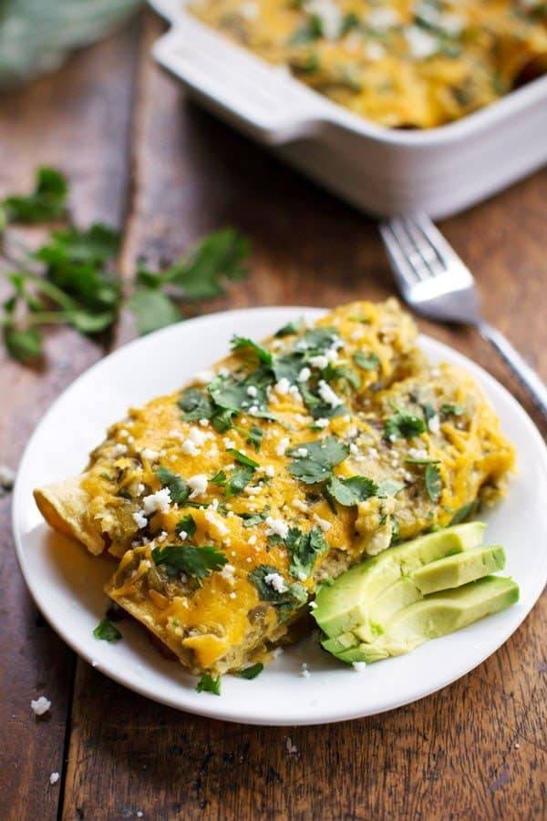 Butternut Squash and Mushroom Enchiladas with Tomatillo Sauce on a white plate.