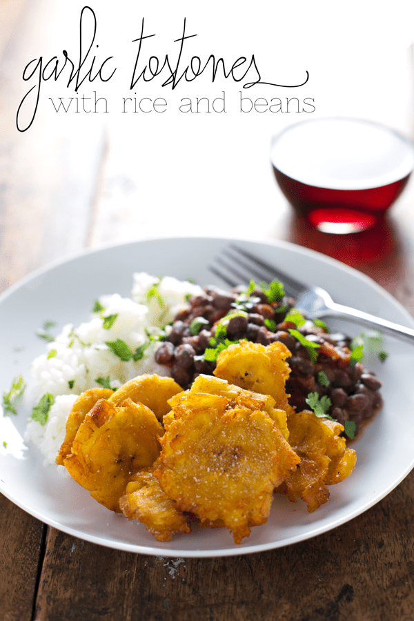 Garlic tostones on a plate with rice and beans.