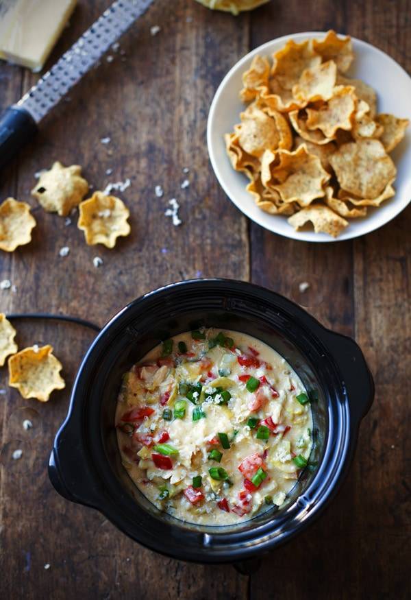 Crab and Artichoke Dip in a slow cooker and a plate of chips.