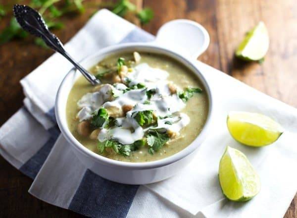 Soup in a bowl with limes and sour cream.