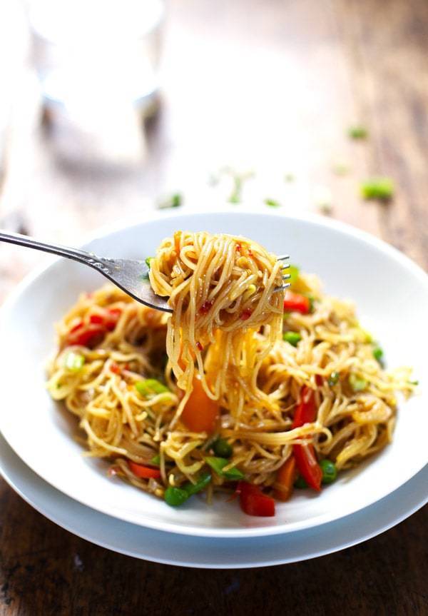 Stir fried Singapore Noodles with veggies on a plate and a fork.