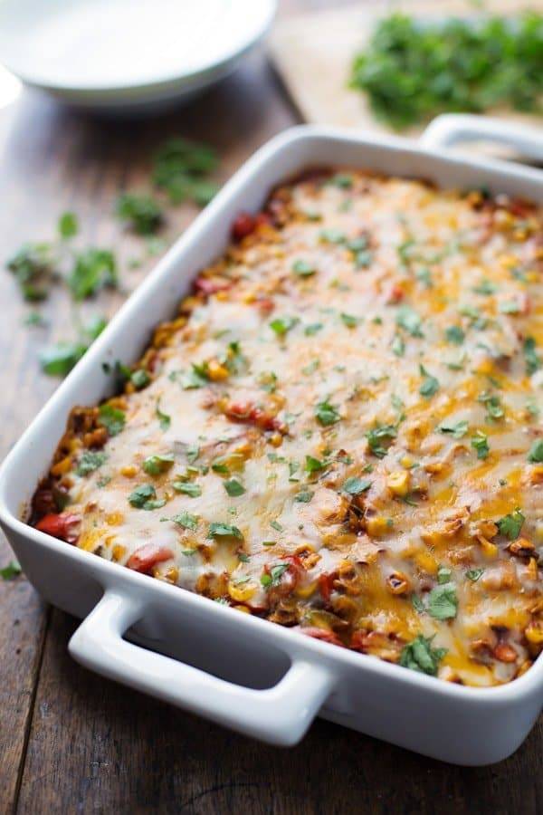 Mexican casserole in a white pan with cilantro in the background. 