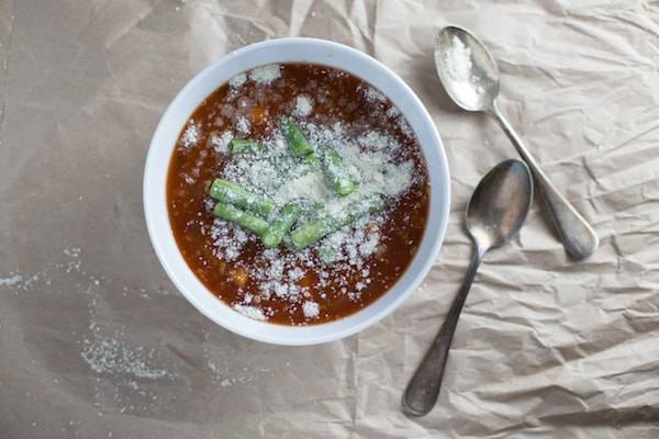 Soup in a bowl with green beans and cheese topping.