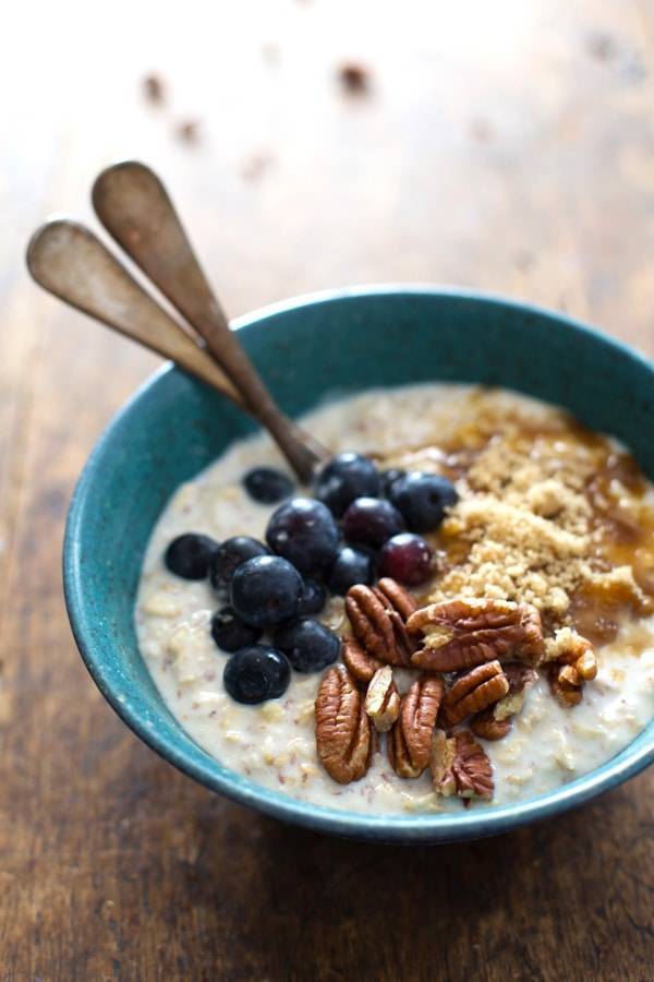 Oats in a blue bowl with flax, blueberry, and vanilla yogurt.