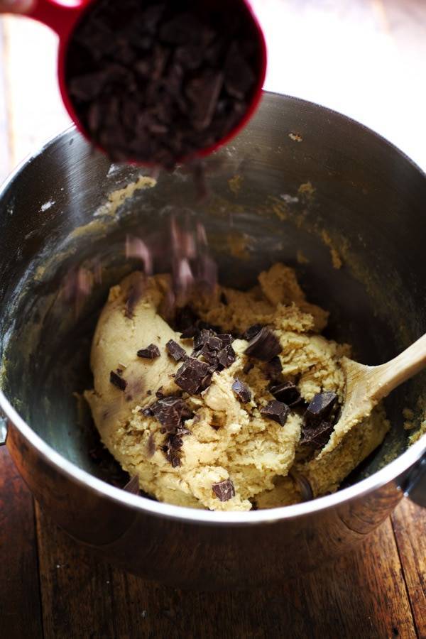 Cookie dough in a mixing bowl with chocolate chunks.