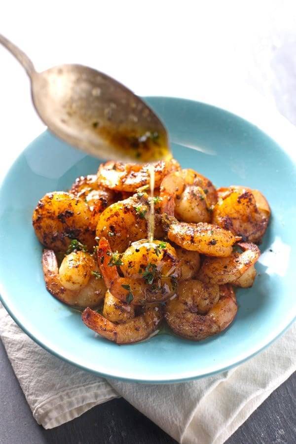 Orange Brown Butter Shrimp with drizzle in a blue bowl.