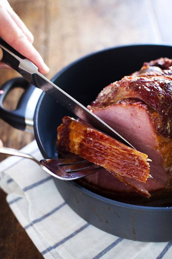 Ham in a black dish with a fork and a knife.