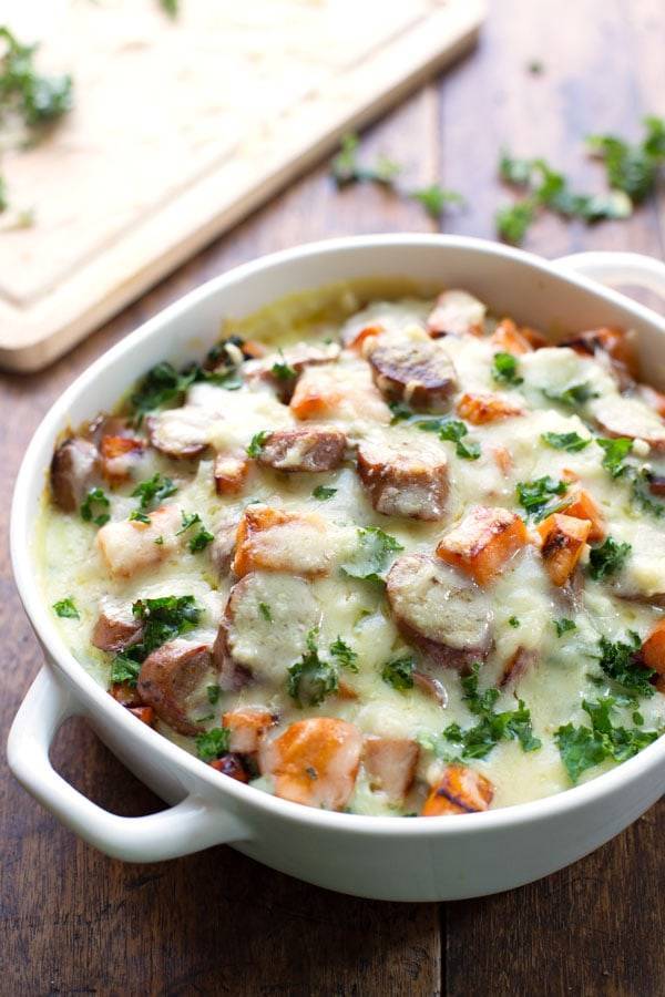 Sweet Potato, Kale, and Sausage Bake with White Cheese Sauce in a white baking dish.