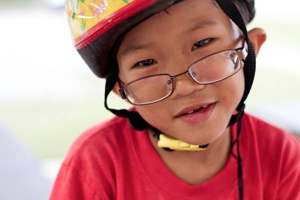 Young boy with glasses wearing a helmet.