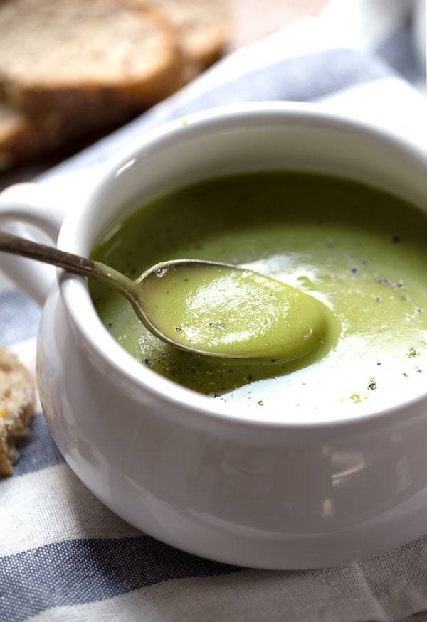 Creamy Potato Kale Soup in a white bowl and on a spoon.