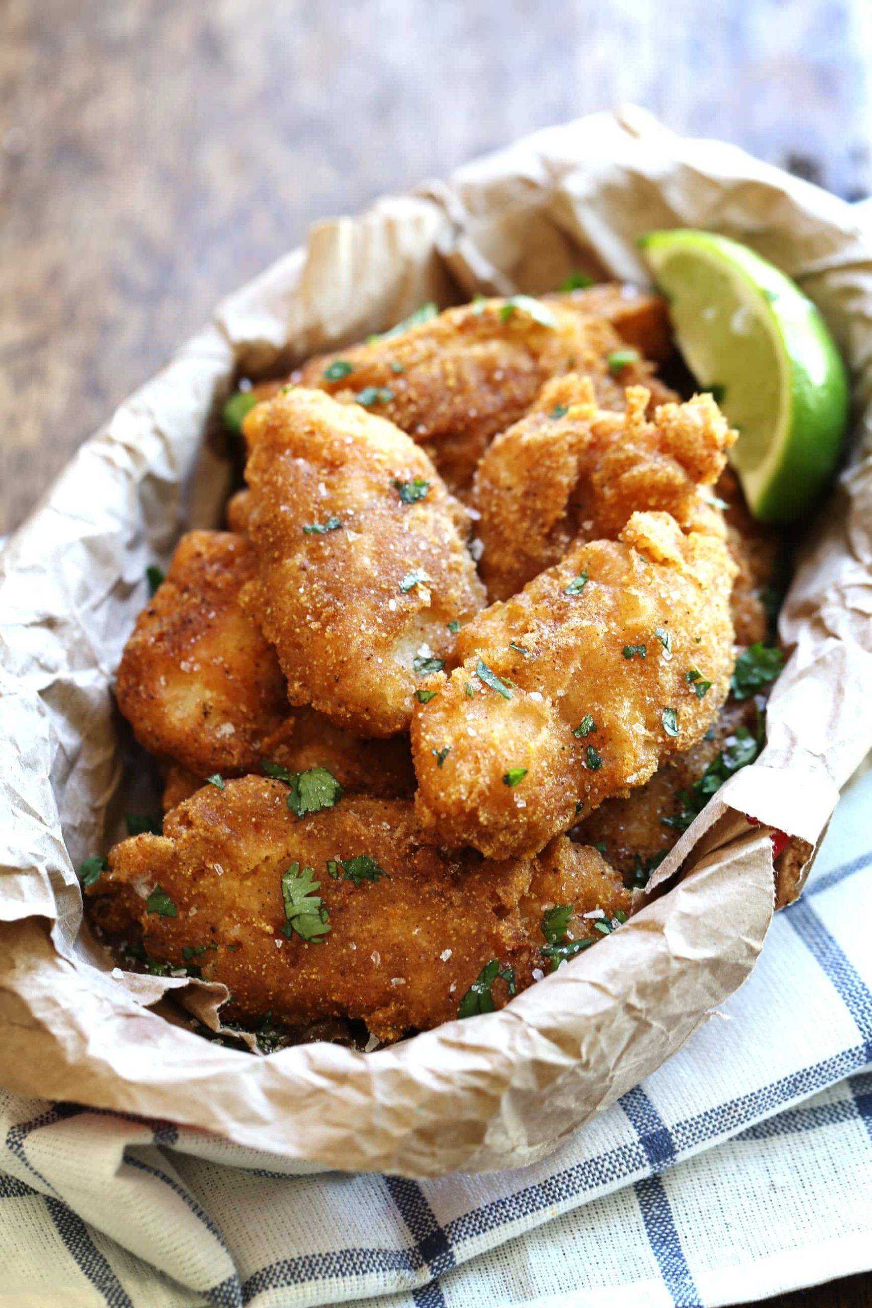Crispy fried fish in a bowl with a lime.