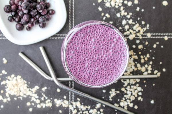 Purple smoothie with frozen blueberries and steel straws.