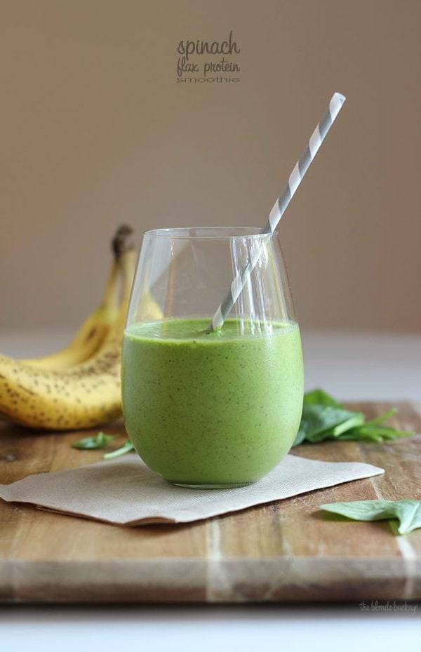 Green spinach smoothie in a glass with a straw.