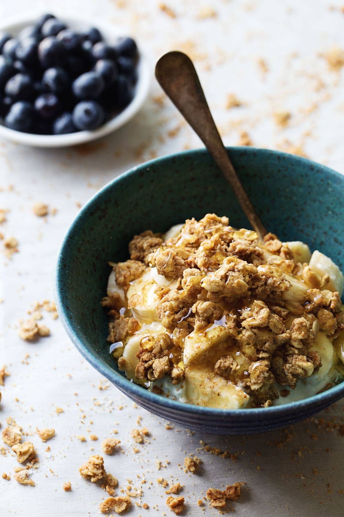Granola on top of bananas in a blue bowl.