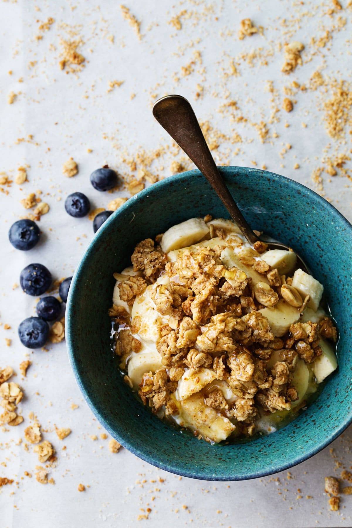 Big Cluster Peanut Butter Granola with bananas and blueberries in a blue bowl.