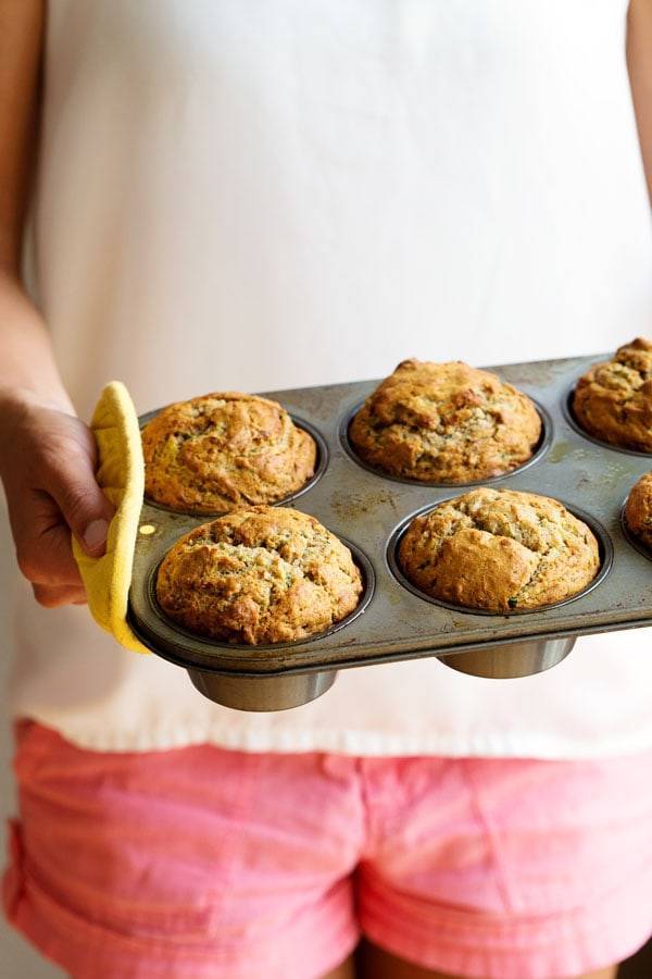 Woman holding muffins in a muffin tin.