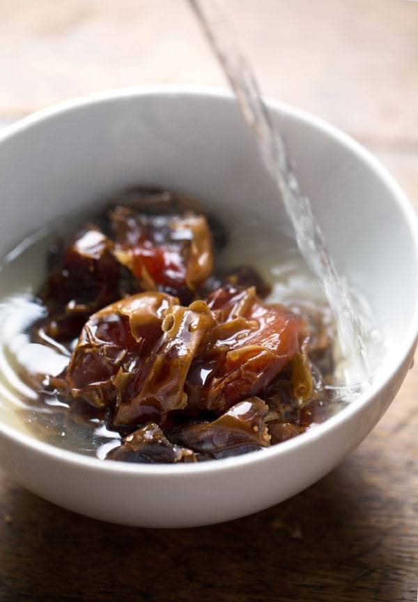 Dates in water in a white bowl.