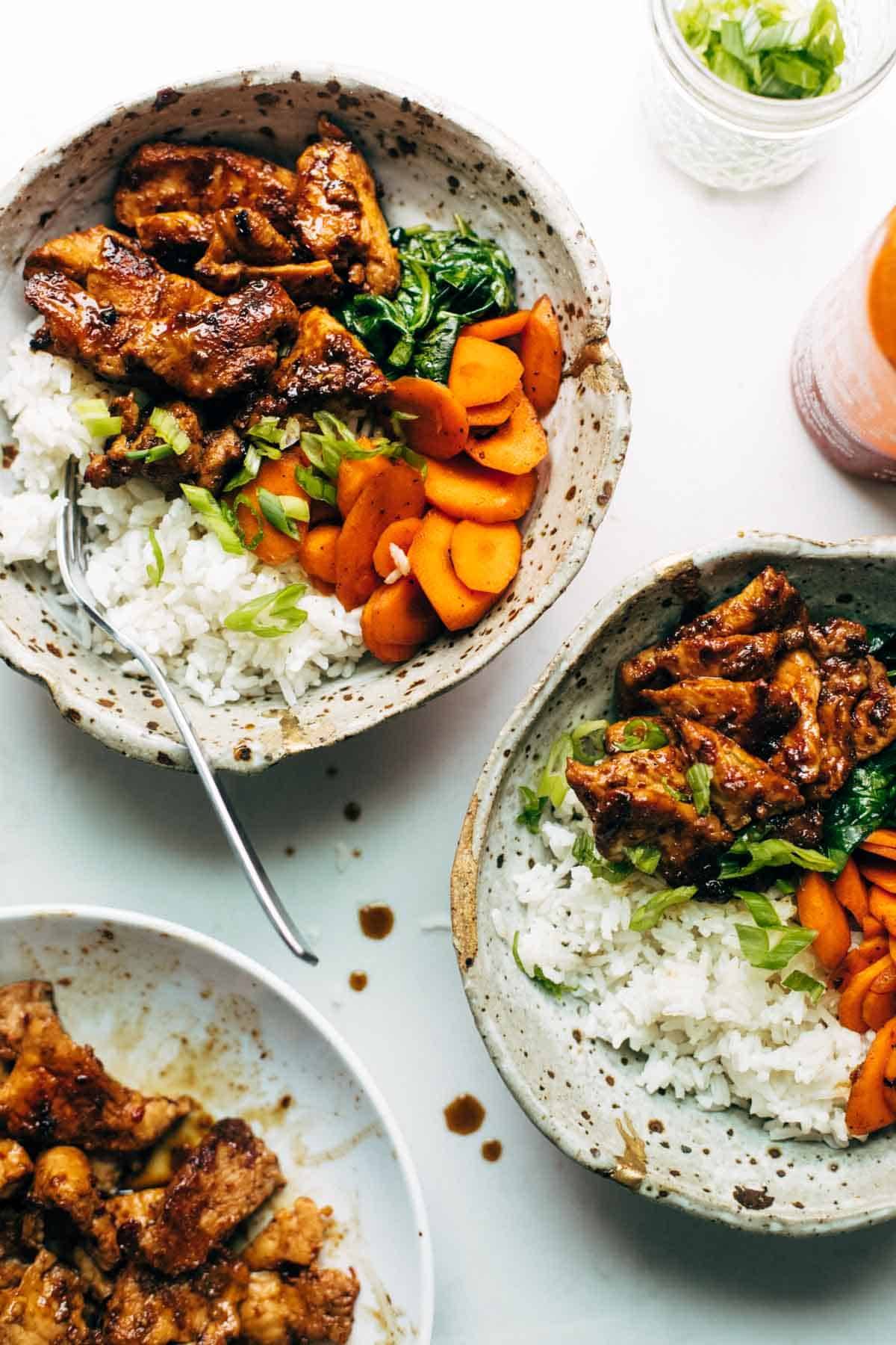 Spicy pork in bowls with veggies and rice.