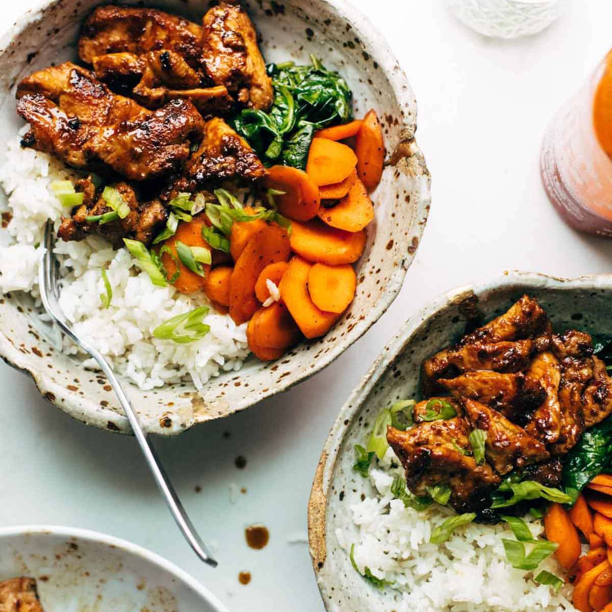 Spicy pork covered in sauce, wilted spinach, and carrots with white rice.