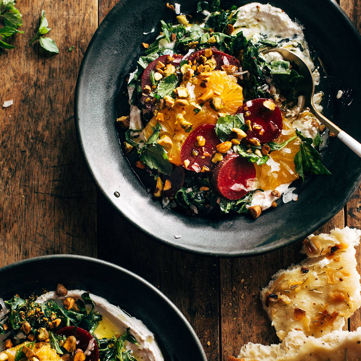 Bowl with kale, beets, oranges, and creamy cheese with a spoon.