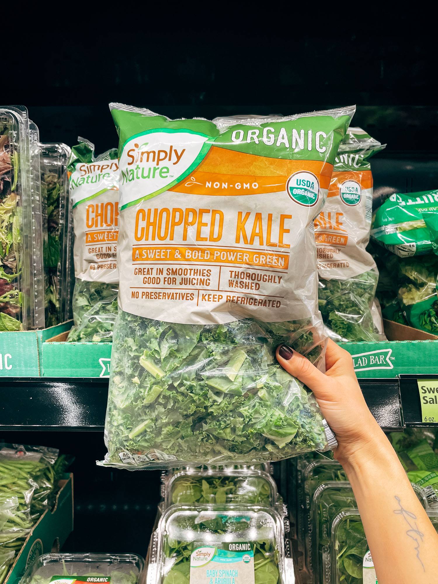 White hand holding a bag of chopped kale