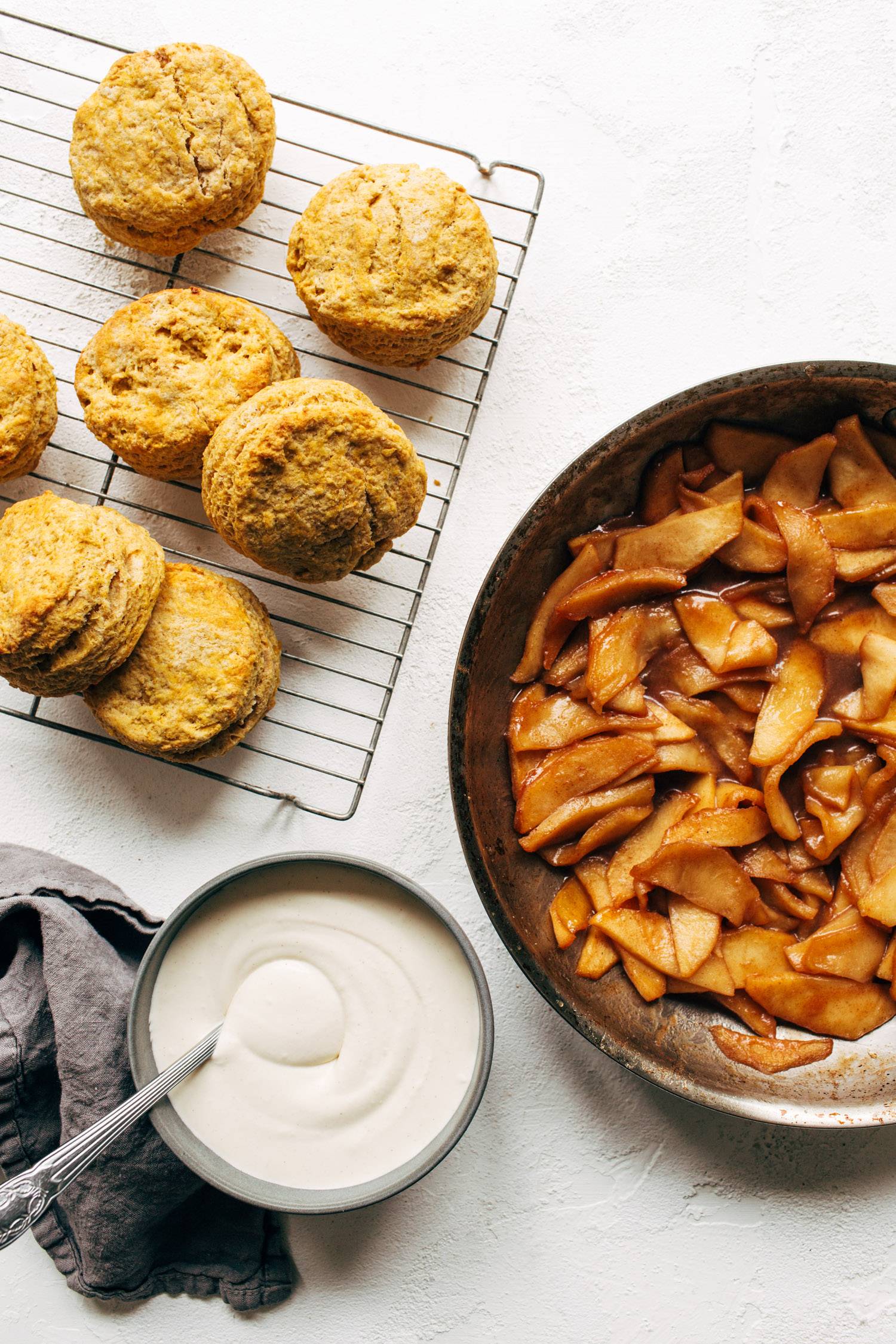 Pumpkin biscuits on a cooling rack with apples in a pan.