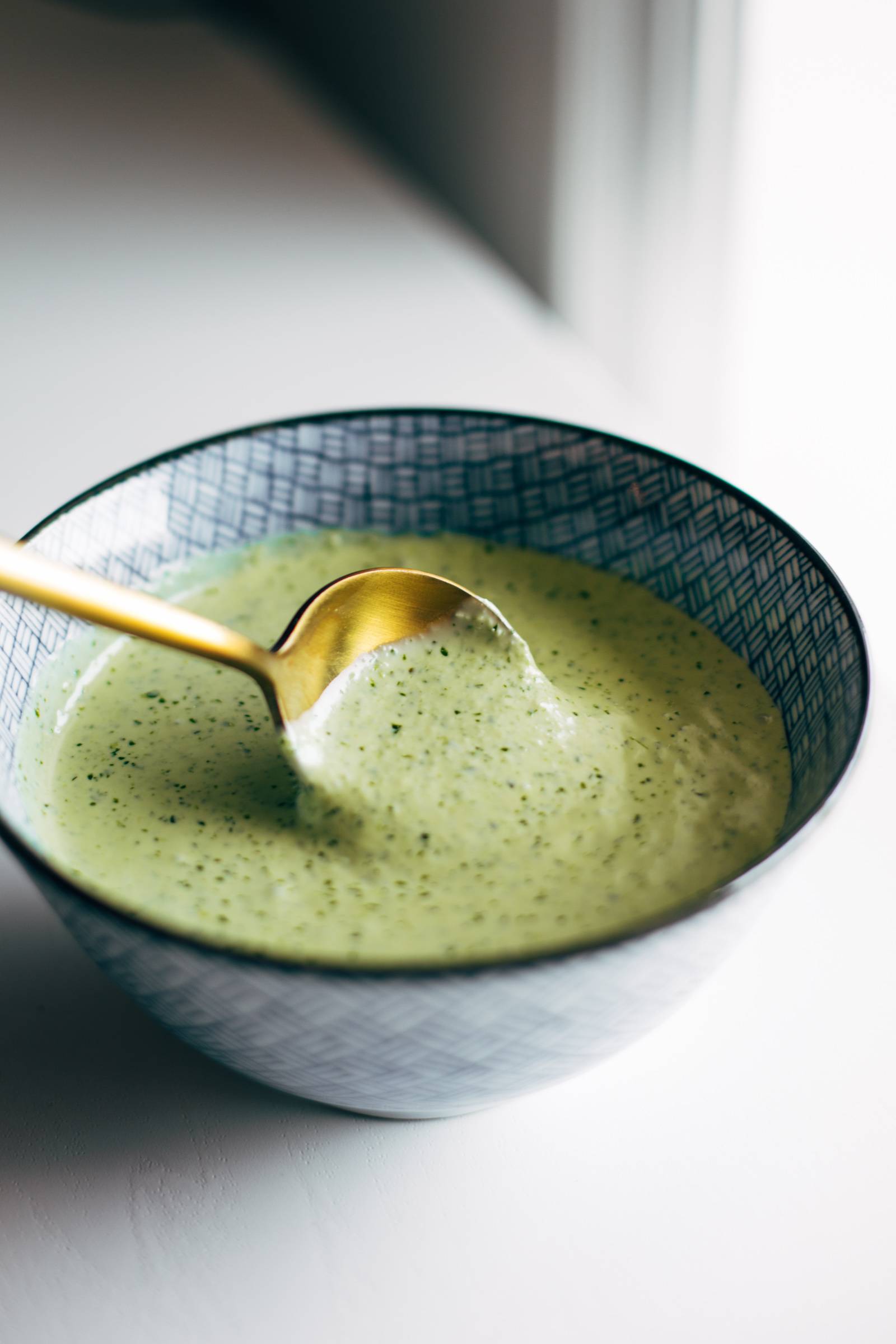 A golden spoon dips into a bowl of aji verde