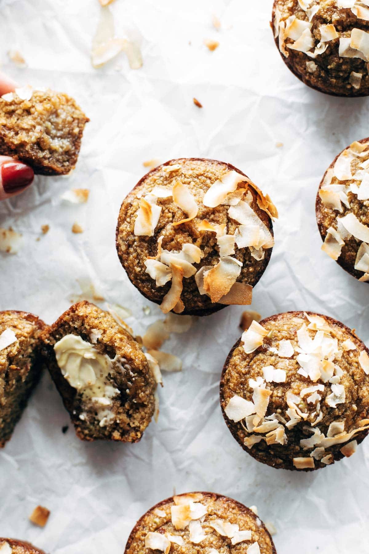 Apple muffins topped with coconut on parchment.