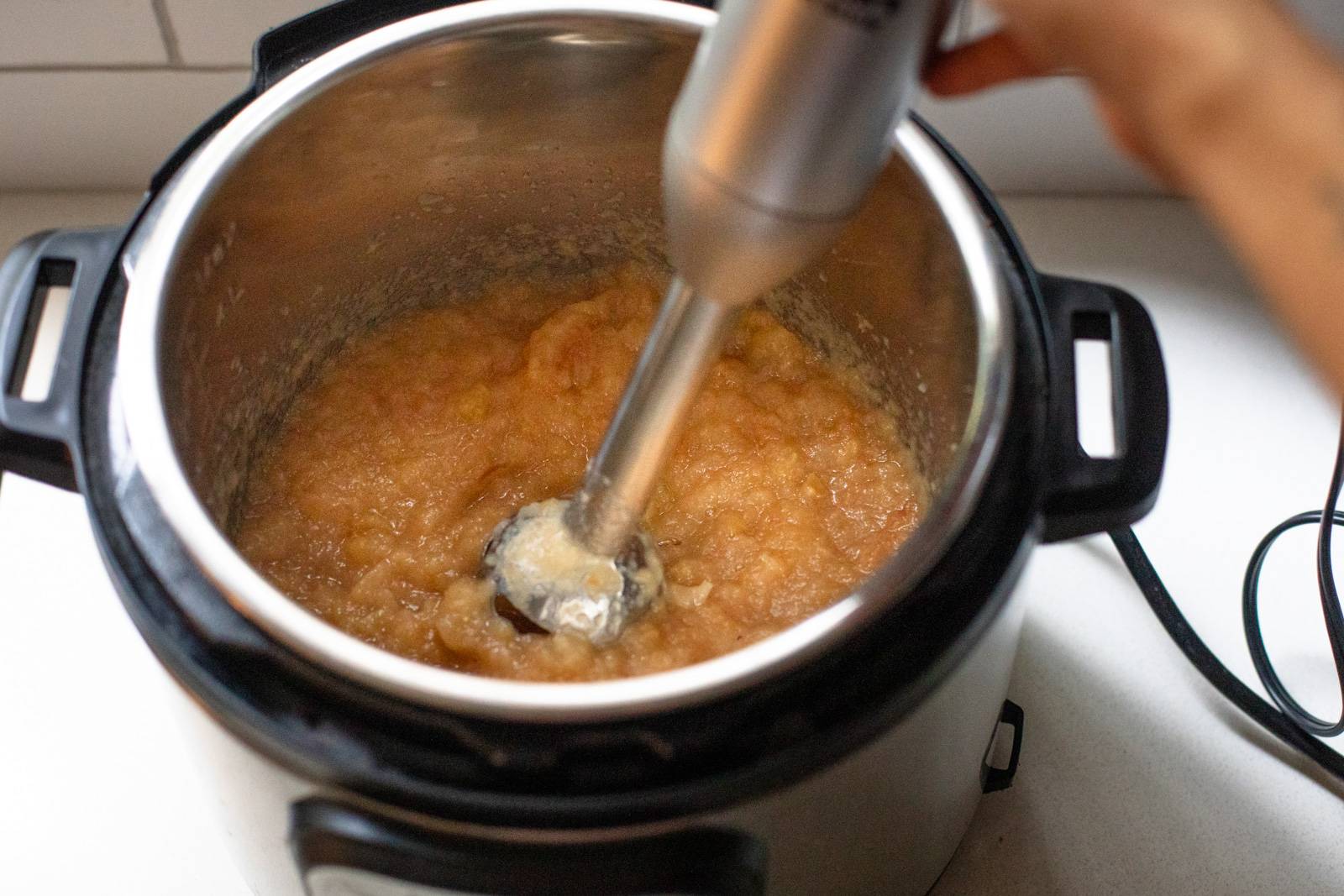 Blending applesauce in the Instant Pot using an immersion blender.