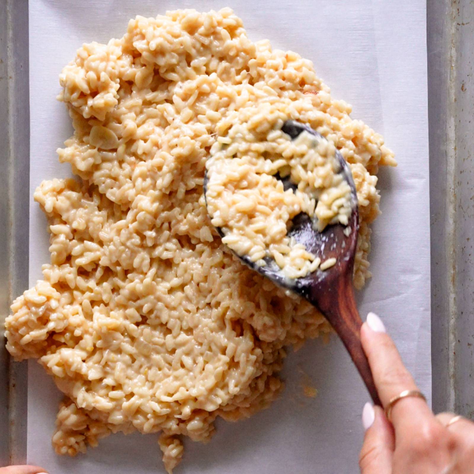 Spreading risotto on a sheet pan.