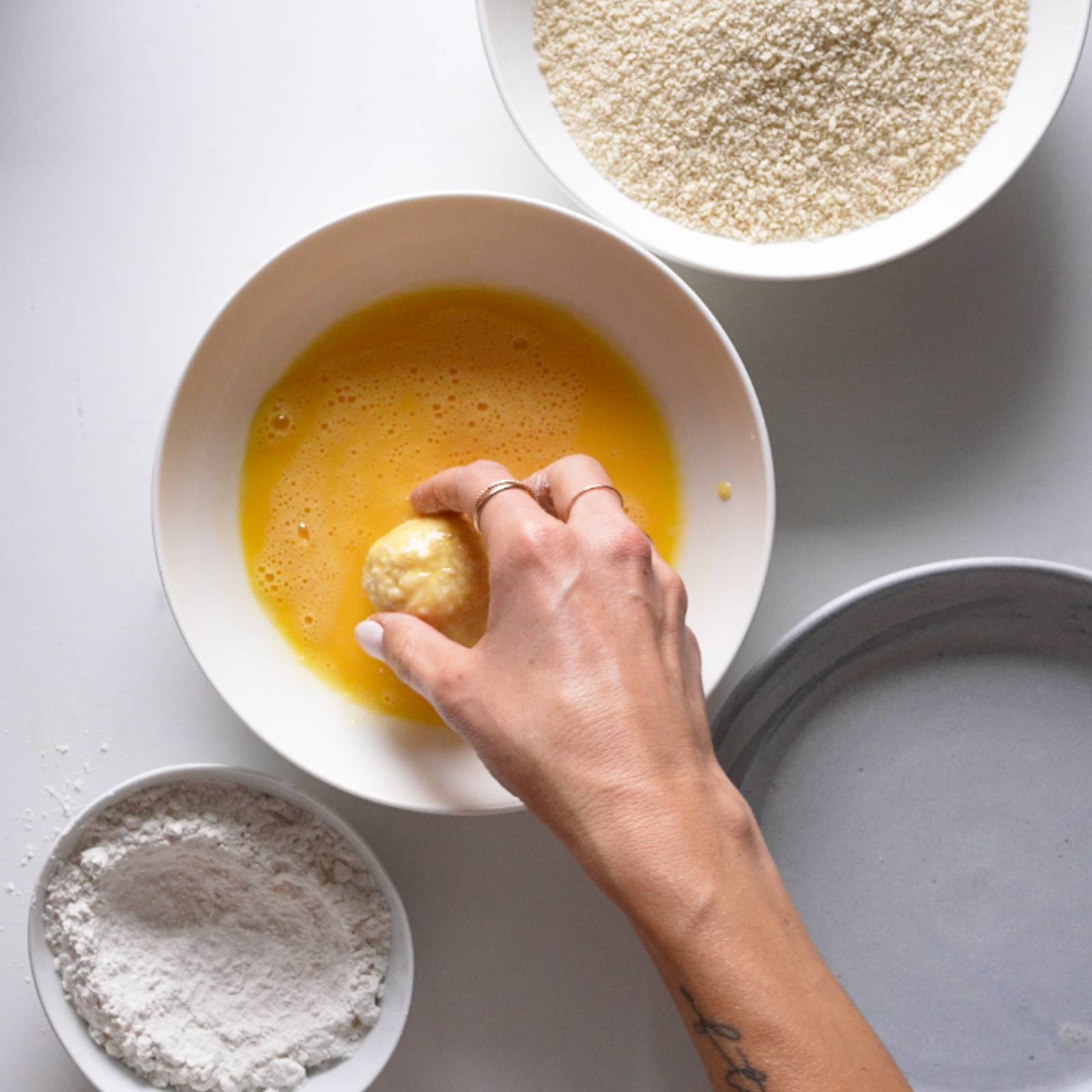 Dipping a ball of arancini in eggs.