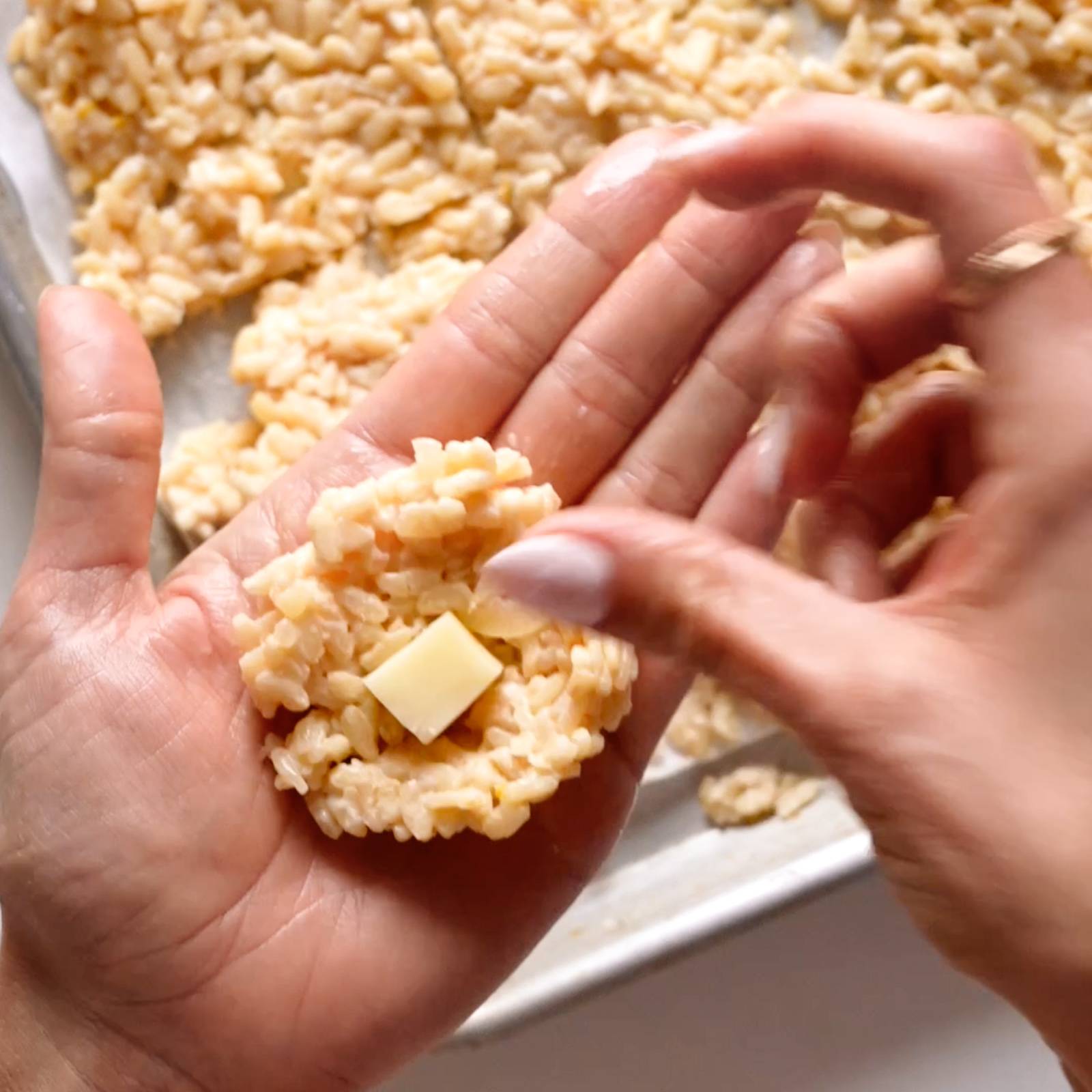 Creating a ball of arancini with cheese in the middle.