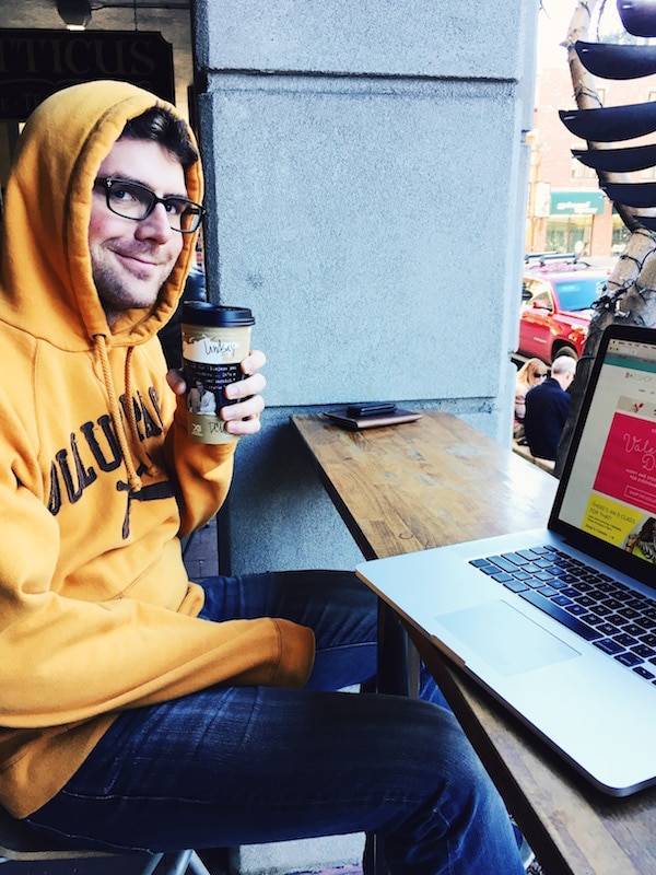 Man wearing a hood holding coffee.
