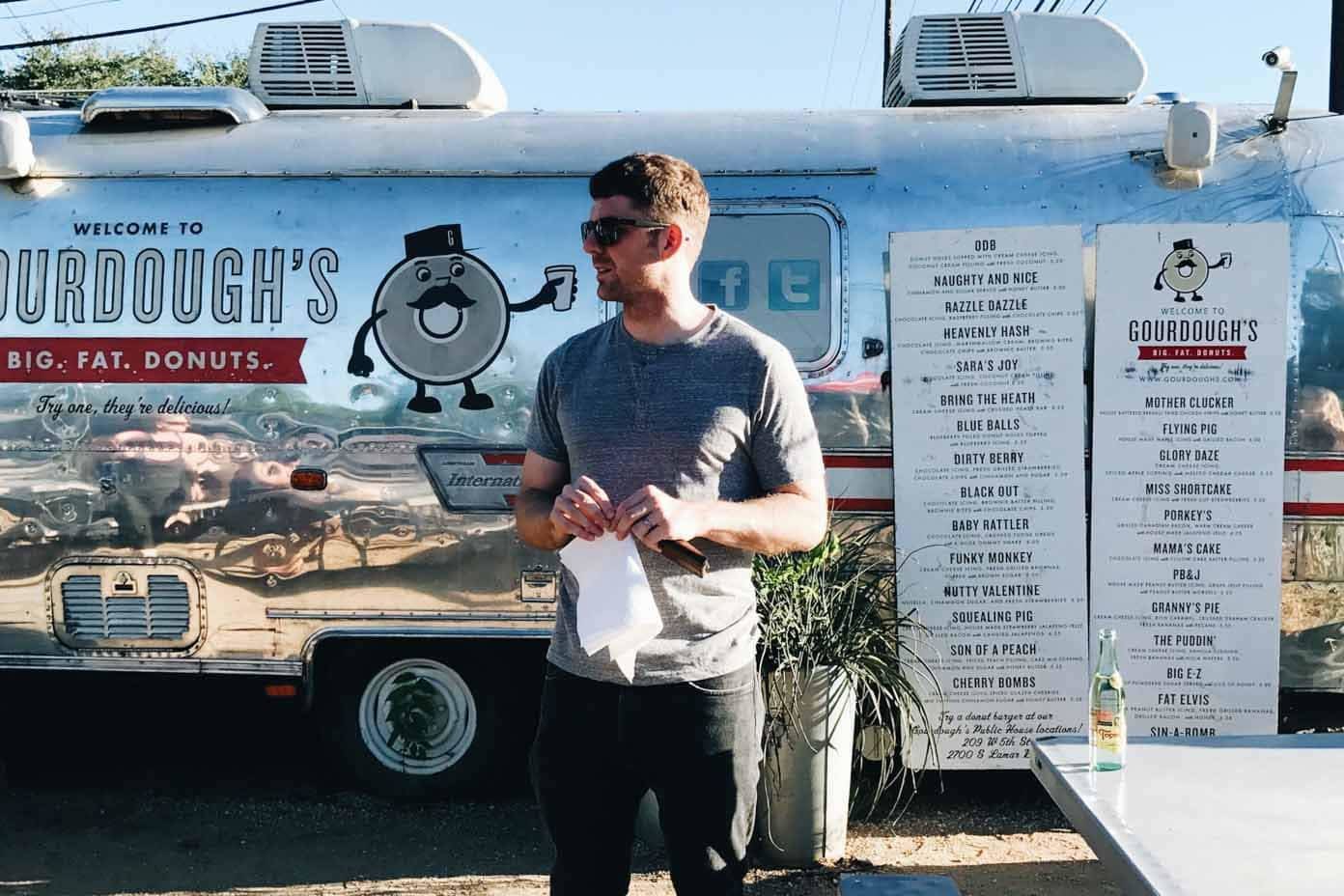 Man standing in front of a donut truck.