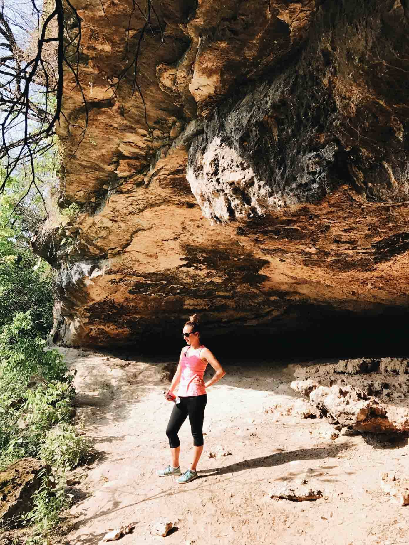 Woman standing under large rocks.