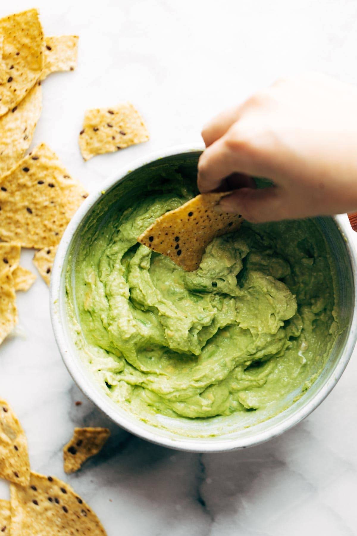 Creamy Avocado Dip in a bowl with chip dipping in.
