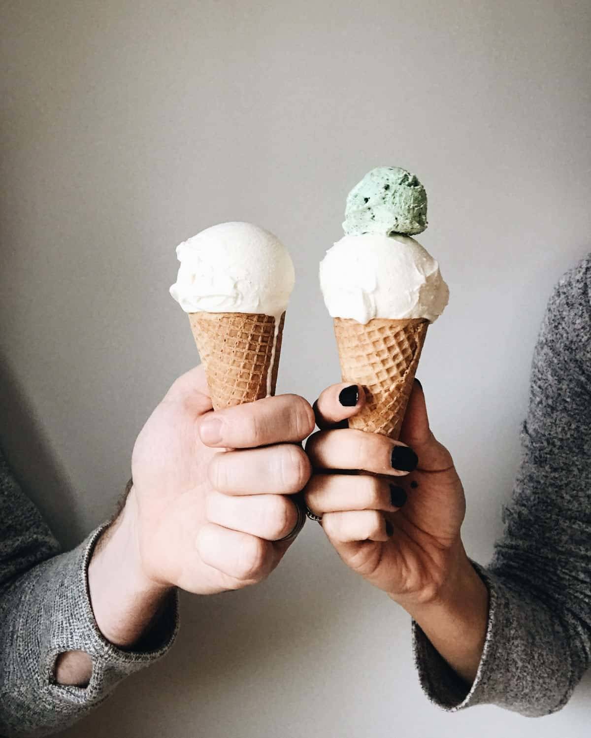 Two hands holding ice cream cones.