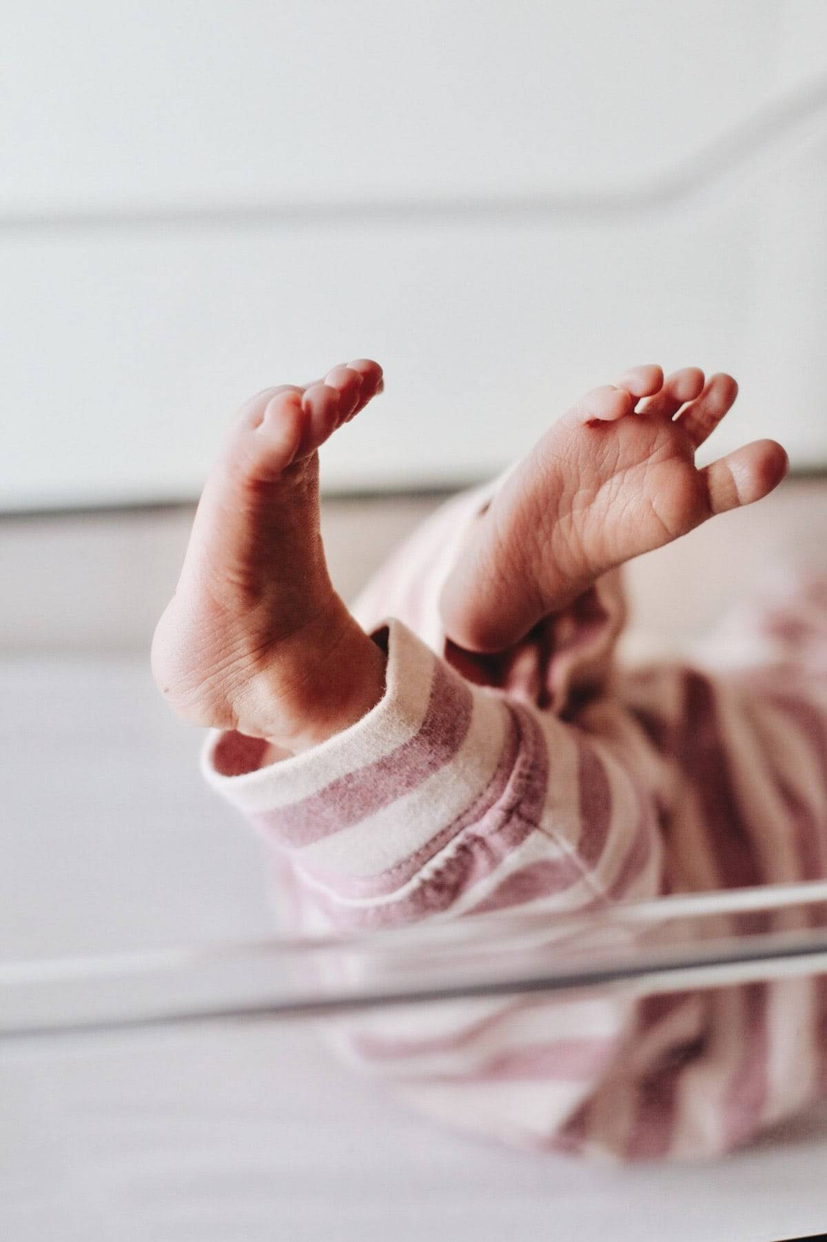 An infant baby laying on its back with its feet up in the air.