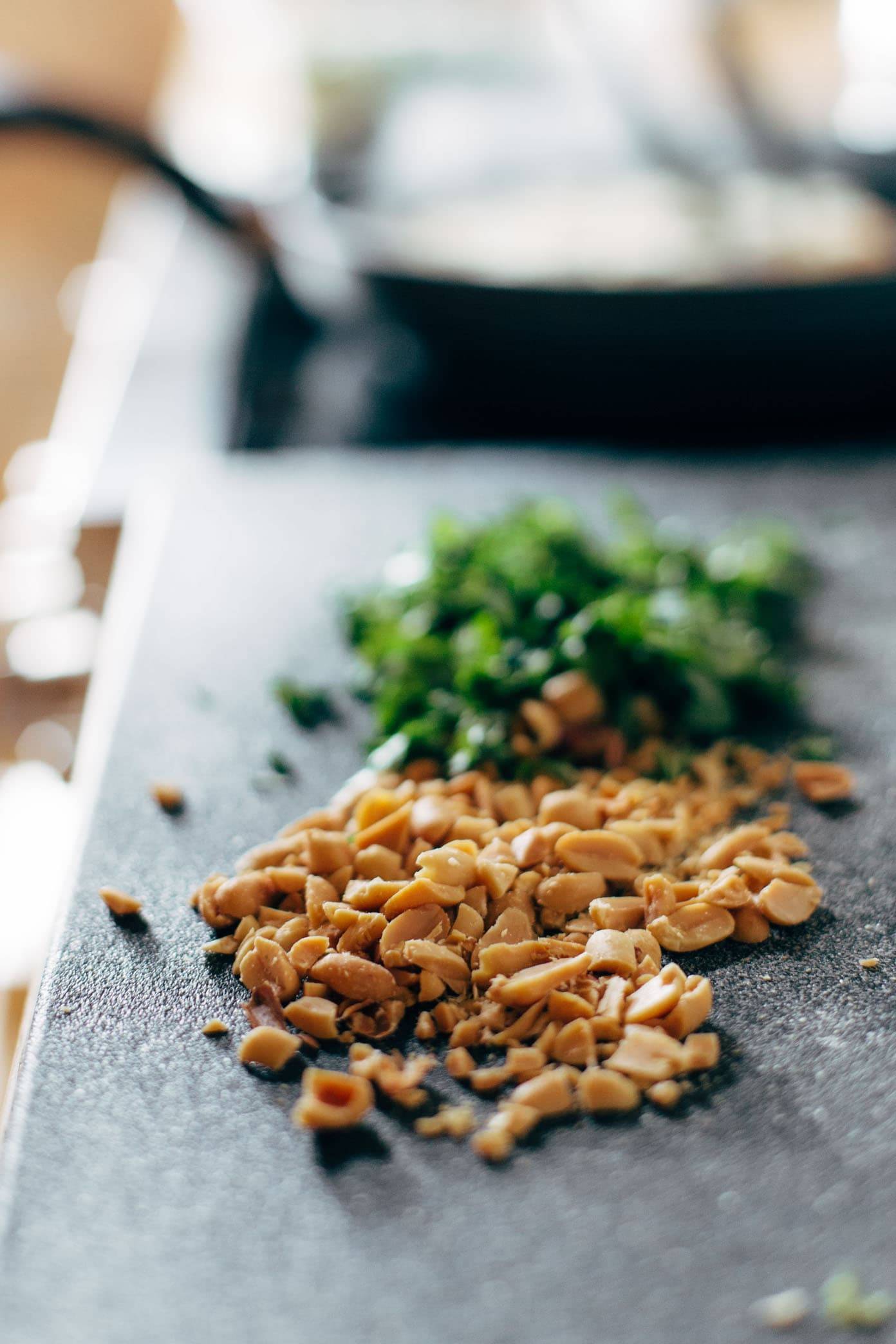 Chopped nuts on a cutting board with herbs.